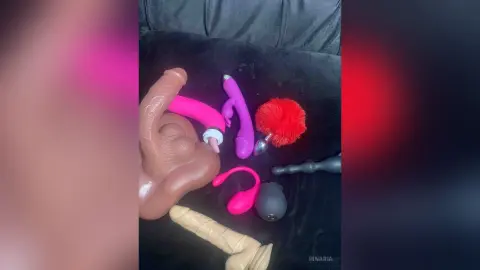 Assorted colorful silicone adult sex toys and vibrators arranged on a dark fabric surface.