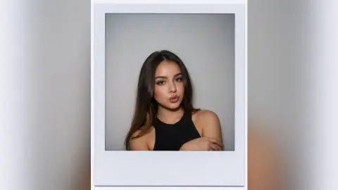 Young woman in a black halter top posing for a moody studio portrait in a white polaroid frame.