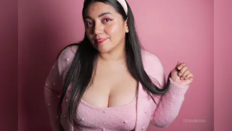 Smiling woman in a soft pink fuzzy cardigan posing against a pink background with a dreamy mood.