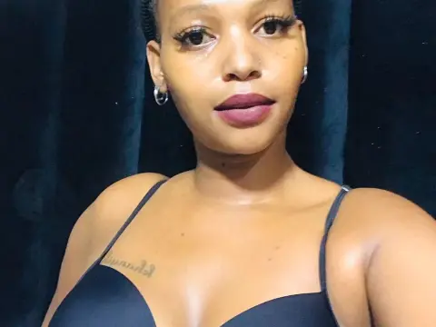 Close-up portrait of a smiling Black woman in a black camisole against a dark backdrop.