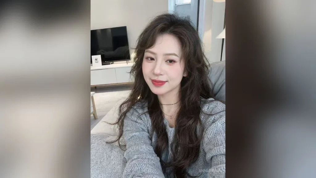 AnnLinMei — AnnLinMei smiles while sitting on a grey sofa wearing a grey sweater.