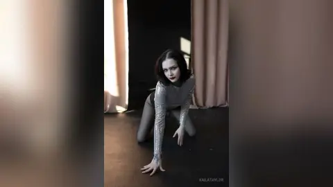 Moody portrait of a woman in a silver sequin bodysuit posing in a dark studio setting.