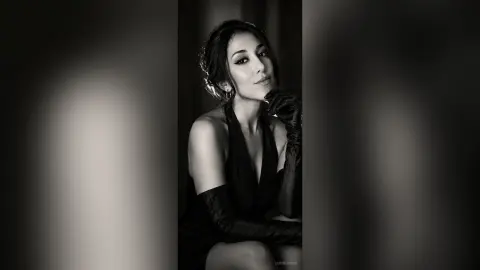 Elegant woman in a black evening gown and long gloves posing for a moody black and white portrait.