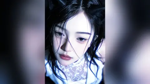 HedyIvy looks into the camera with long black hair and a white lace top against a dark background.