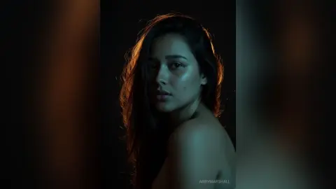 Moody portrait of a young woman with glowing skin in dramatic low-light studio lighting.