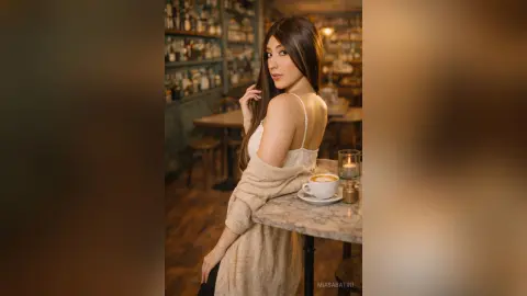 Young woman in a white tank top and beige cardigan sitting at a cafe table with coffee in a moody setting.