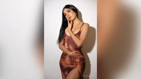 Elegant woman in a bronze satin slip dress posing against a white background for a sophisticated fashion look.
