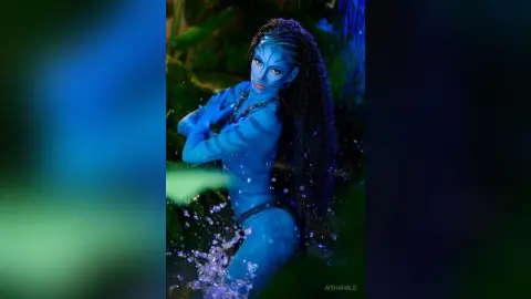 Blue skin Na'vi woman in tribal attire posing in a mystical glowing jungle setting.