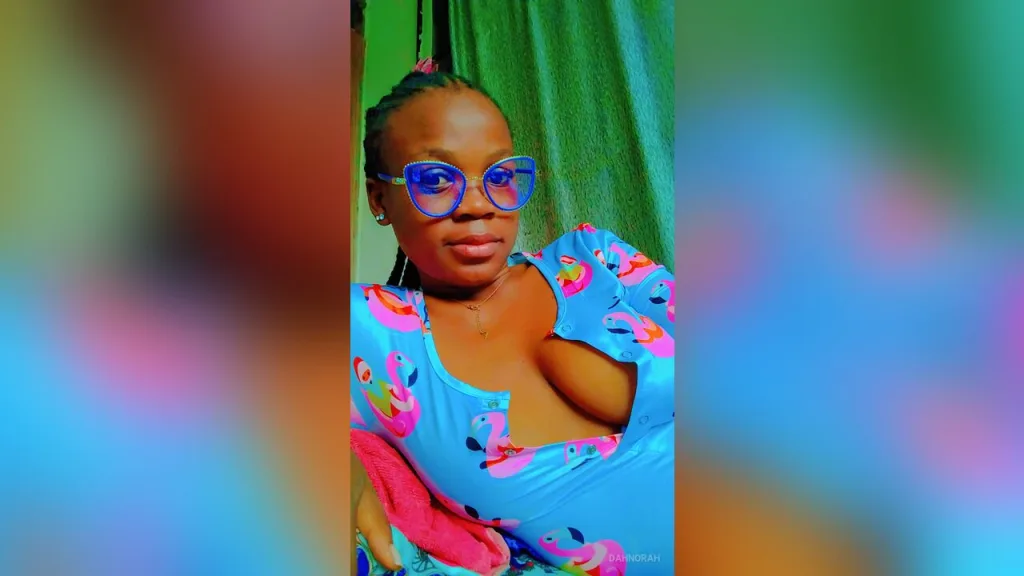 DahNorah wears blue glasses and a light blue patterned tank top while looking into the camera.