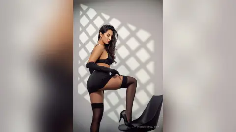VeronicaValdez poses in a black crop top and mini skirt with long gloves and black thigh-high stockings.