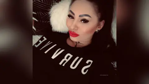DeeaAnderson wears a black t-shirt with white text while lying back against a white furry surface.