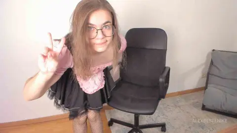 Young woman in a pink and black gothic lolita dress making a peace sign in a bright room.