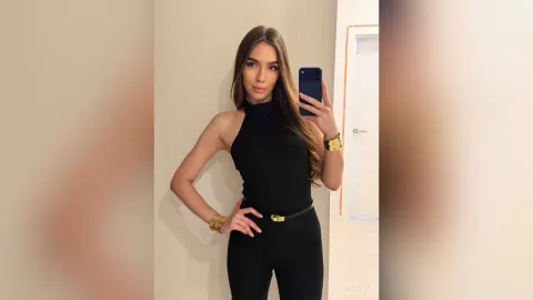 AmiliRay — AmiliRay poses for a mirror selfie wearing a tight black halter bodysuit and gold bracelets.