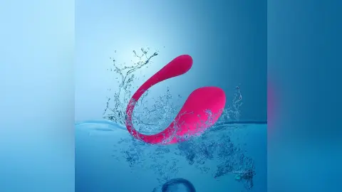Vibrant pink designer accessory splashing into clear blue water with refreshing liquid droplets.