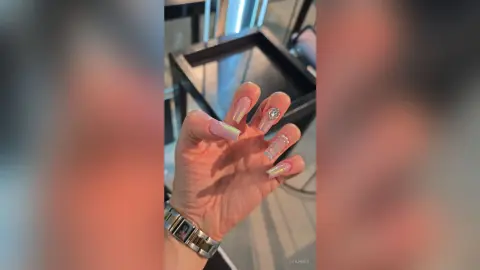 Close-up of a hand featuring long almond-shaped nails with iridescent pastel ombre and rhinestone nail art.
