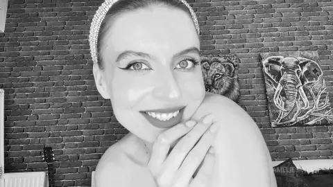 Smiling woman with a sparkly headband posing in a room with brick walls and elephant wall art.