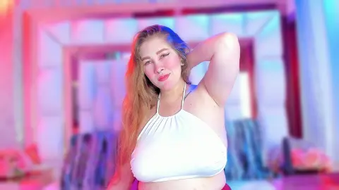 Blonde woman in a white halter top posing in a room with vibrant pink and blue neon lighting.