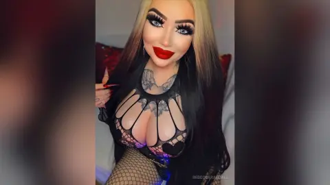 RebeccaRandall — Glamorous woman with long dark hair and bold red lips wearing a black cutout lace bodysuit in a moody setting.