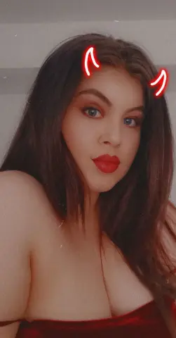 Young woman with red lipstick and devil horns filter posing in a red outfit for a playful moody look.