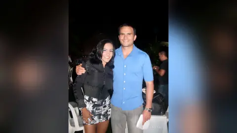 Smiling couple in casual evening attire posing together at an outdoor night event.