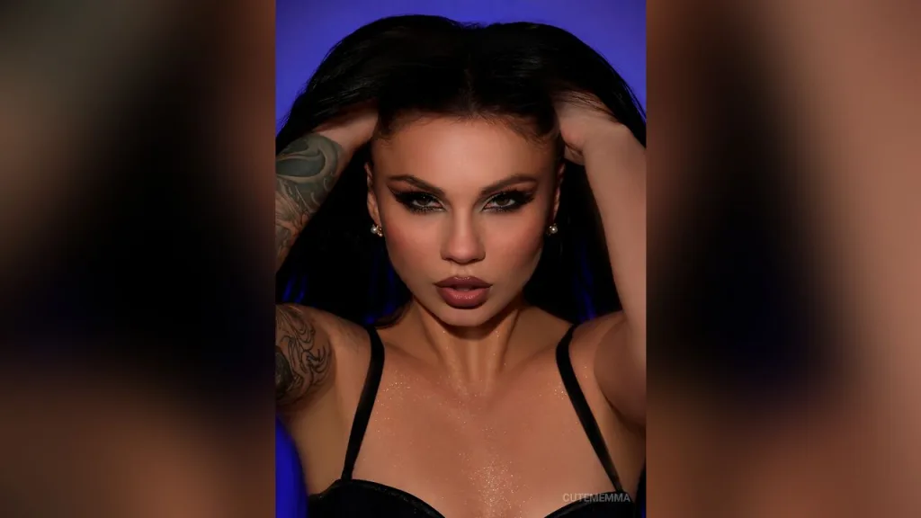 Glamorous woman with dramatic eye makeup and dark hair posing against a vibrant pink background.