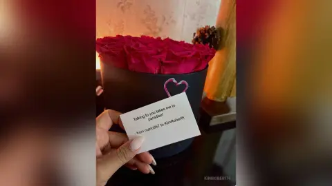 KimRoberth holds a card next to a large box of deep red roses.