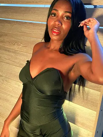Beautiful Black woman in a sleek black strapless bodysuit lounging on a wooden deck in warm sunlight.