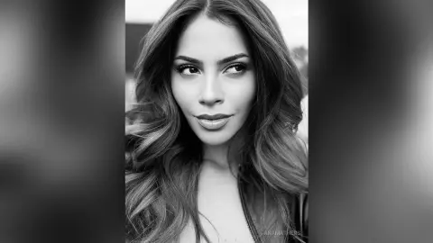 AnaMathers poses with long, wavy hair and heavy eye makeup, looking off-camera in a black and white close-up.