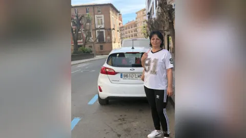 JesicaMaily — JesicaMaily stands on a city street wearing a white jersey and black leggings next to a white car.