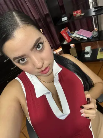 SophiRioss wearing a red and white collared tank top, looking up at the camera with long dark hair and a nose ring.