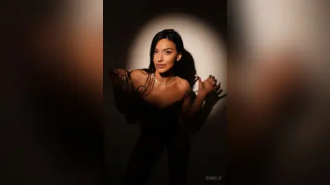 Iza — Elegant woman in a black evening dress posing under dramatic studio lighting for a moody portrait.