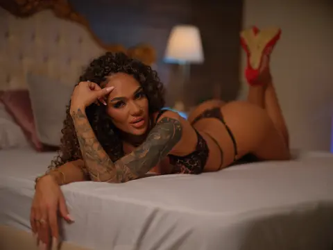 Curvy woman with curly hair in leopard print lingerie relaxing on a white bed in a cozy bedroom setting.