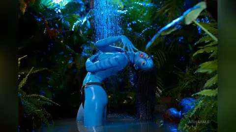 Blue skinned fantasy woman in a dark jungle setting under a waterfall, creating a mystical and ethereal mood.