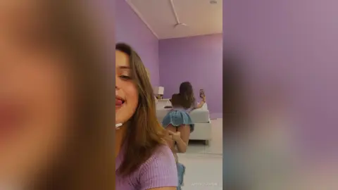 Young woman in a purple top taking a selfie in a modern lavender bedroom with a cozy, relaxed mood.