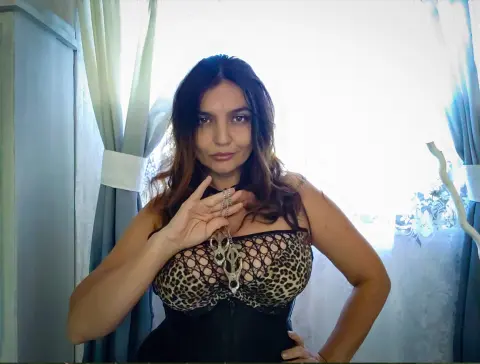 DominaPaulina wears a leopard print bra and black corset while posing in front of a window.