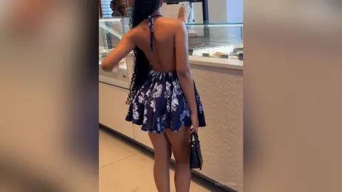 Woman in a navy floral backless mini dress standing in a modern cafe setting.