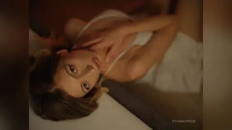 Blonde woman in a white dress lying on a bed with a dreamy, romantic mood.