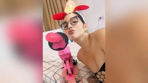 Young woman in red reindeer ears and glasses making a playful pouty face in a bedroom setting.
