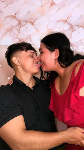 Affectionate young couple in casual summer outfits sharing a romantic moment against a marble background.