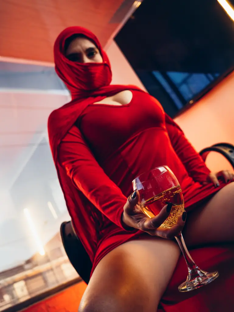 Smiling woman in a red long-sleeve dress sitting in a modern bright room.