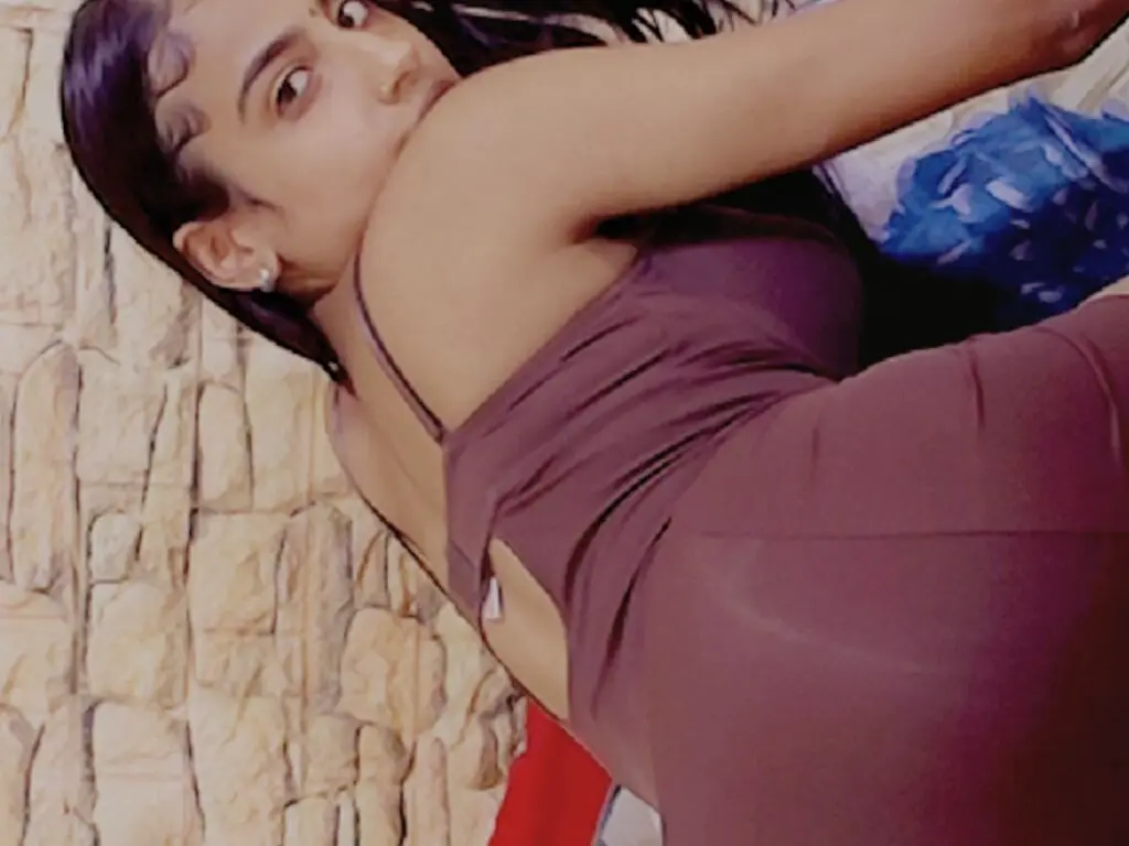 Young woman in a sleek mauve dress posing against a textured stone wall in a relaxed mood.