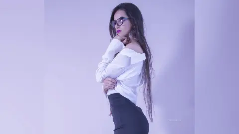 Stylish woman in a white blouse and black skirt posing elegantly against a light purple studio background.