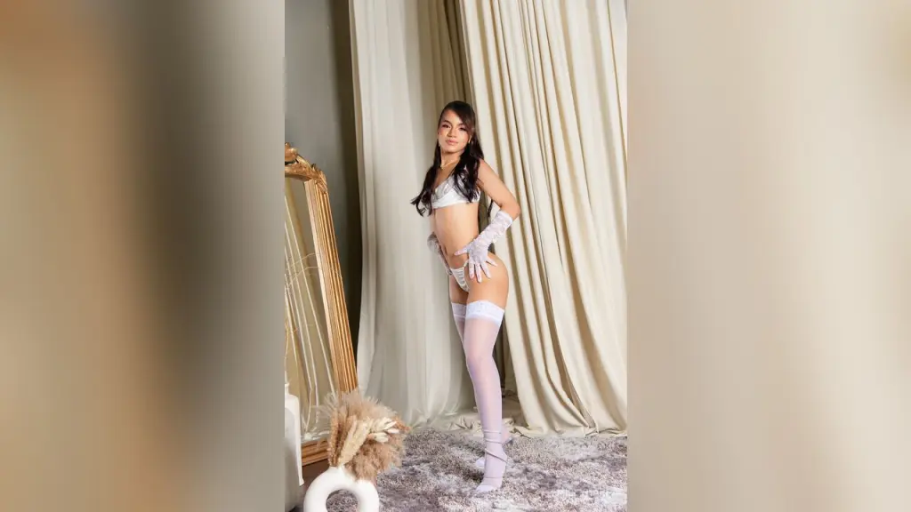 EmillyHarp โ EmillyHarp poses in white lace lingerie and thigh-high stockings against cream curtains.