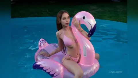 Young woman in pink bikini relaxing on a large pink flamingo float in a blue swimming pool.