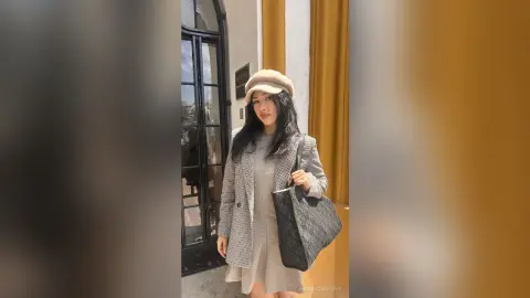 Stylish woman in a grey plaid blazer and beige beret carrying a black tote bag outdoors.