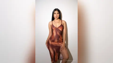 Young woman in a brown satin slip dress posing against a white studio background with elegant lighting.