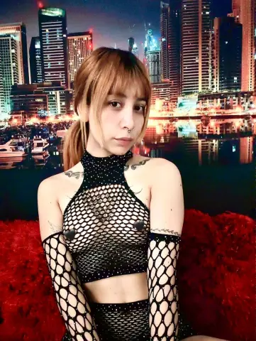 Samlion20 wears a black mesh crop top and matching fingerless gloves, posing against a bright city skyline background.