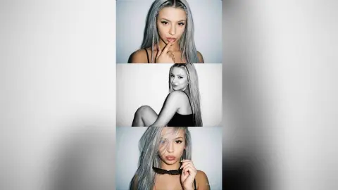 Kalira poses with her long, silver-grey hair, wearing a black top and black sunglasses while looking directly at the camera.