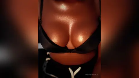 Close-up of a woman in a black bikini top with glowing skin in warm, moody lighting.