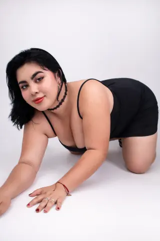 Curvy woman in a black bodysuit posing on a white background with a confident and minimalist mood.